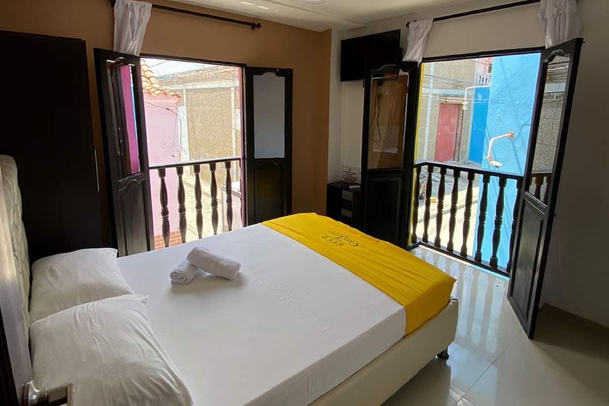 A hotel room with a bed, a balcony, and a view of the outside.