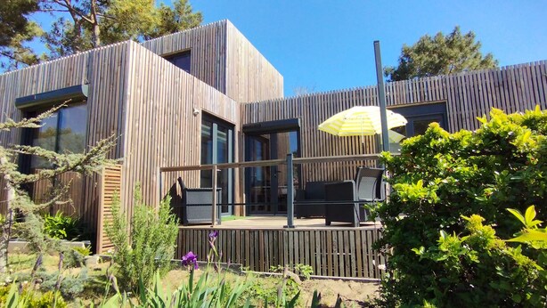 A modern wooden house with large windows, a deck, and a yellow umbrella. - Air-conditioned mini-house near the beaches, built in 2022 (Pornichet)