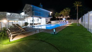 Una casa a due piani con piscina, patio coperto e prato curato.