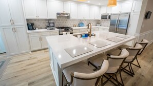 Una cucina moderna con mobili bianchi, elettrodomestici in acciaio inossidabile e un'isola centrale con sgabelli da bar.