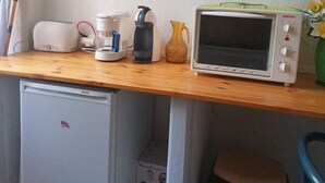 Pieni keittiönurkkaus, jossa on Bosch-merkkinen minijääkaappi, Glénan-merkkinen leivänpaahdin, kahvinkeitin ja pieni uuni.