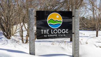 Señalización de 'The Lodge by Sunapee Stays' con un logo que muestra un sol, olas y una montaña.