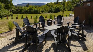 Un área de estar al aire libre con sillas Adirondack y una mesa redonda, rodeada por un patio de grava.