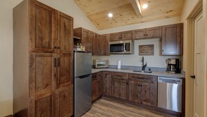 Una cocina con armarios de madera, electrodomésticos de acero inoxidable y techo de madera.