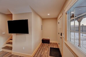 Enjoy a serene view from the large window, with a flat-screen TV and staircase leading to a second floor.