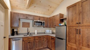 Una cocina con armarios de madera, electrodomésticos de acero inoxidable y techo de madera.