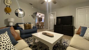 Una sala de estar con sofá, mesa de centro, televisor y ventilador de techo.