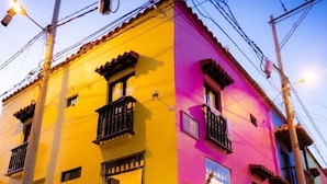 Un immeuble à la façade jaune et rose, doté d’un balcon, avec un vélo garé devant.