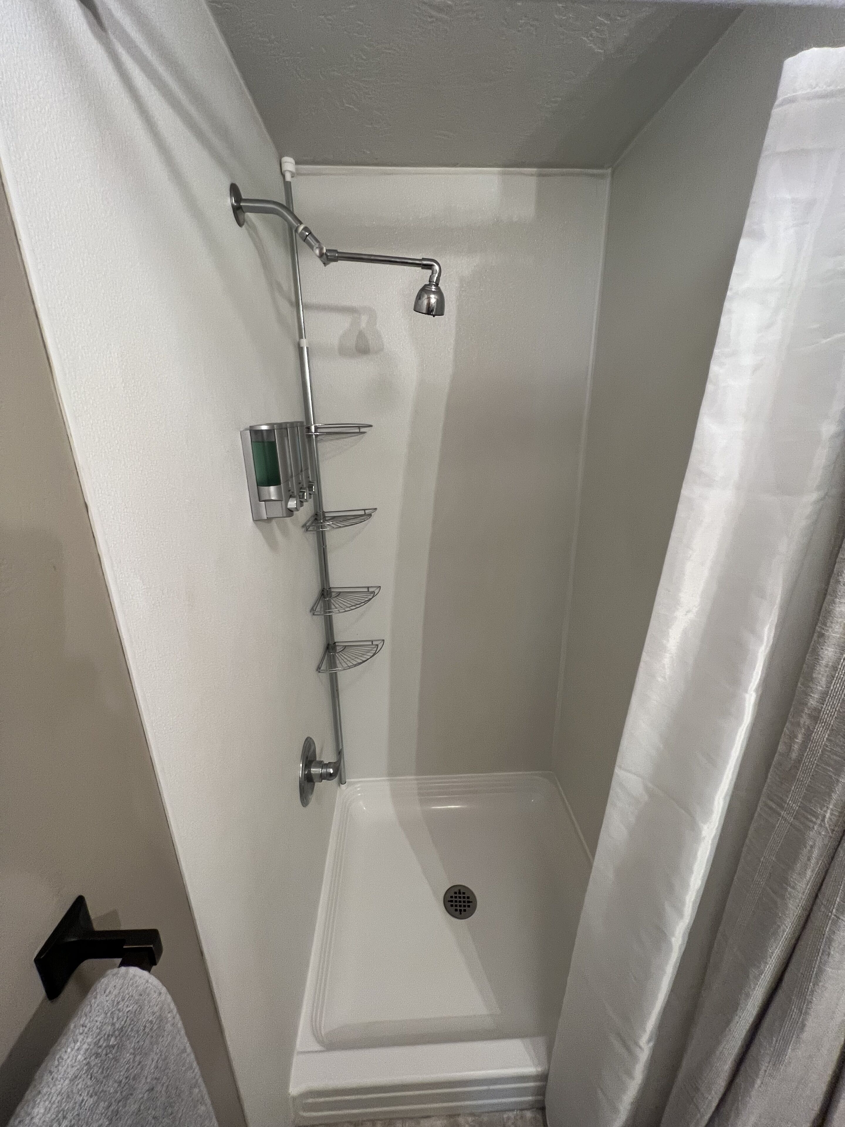 A shower with a glass door, a handheld showerhead, and a wall-mounted faucet.