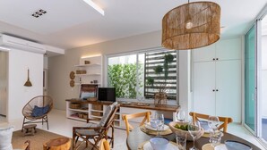 Uma sala de jantar moderna com uma mesa redonda posta para quatro pessoas, rodeada por cadeiras de vime.