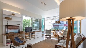 Uma sala de estar moderna com televisão, móveis de vime e vista para a cidade.