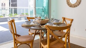 Uma área de refeições com uma mesa redonda, seis cadeiras de madeira, uma luminária pendente trançada e um espelho grande na parede.