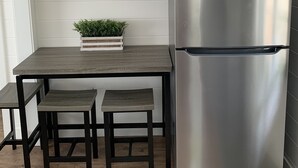 A kitchen with a stainless steel refrigerator, a wooden table with two chairs, and two framed pictures on the wall. - Waterfront property perfect for a relaxing weekend or family get away (Osage Beach)