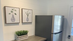 A kitchen with a wooden table, two bar stools, a stainless steel refrigerator, and two framed botanical prints on the wall. - Waterfront property perfect for a relaxing weekend or family get away (Osage Beach)