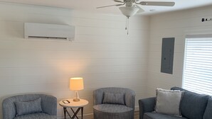 A living room with a ceiling fan, a round table with a lamp, two armchairs, a sofa, and a wooden floor. - Waterfront property perfect for a relaxing weekend or family get away (Osage Beach)