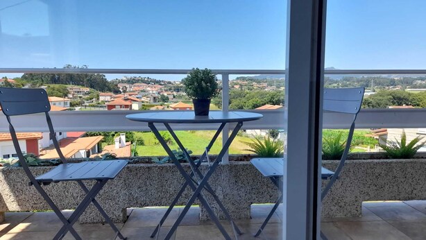 Un balcón con una mesa y dos sillas, con vistas a una zona residencial con casas y vegetación.