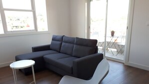 Una sala de estar moderna con un sofá seccional gris, una mesita blanca y un sillón gris.