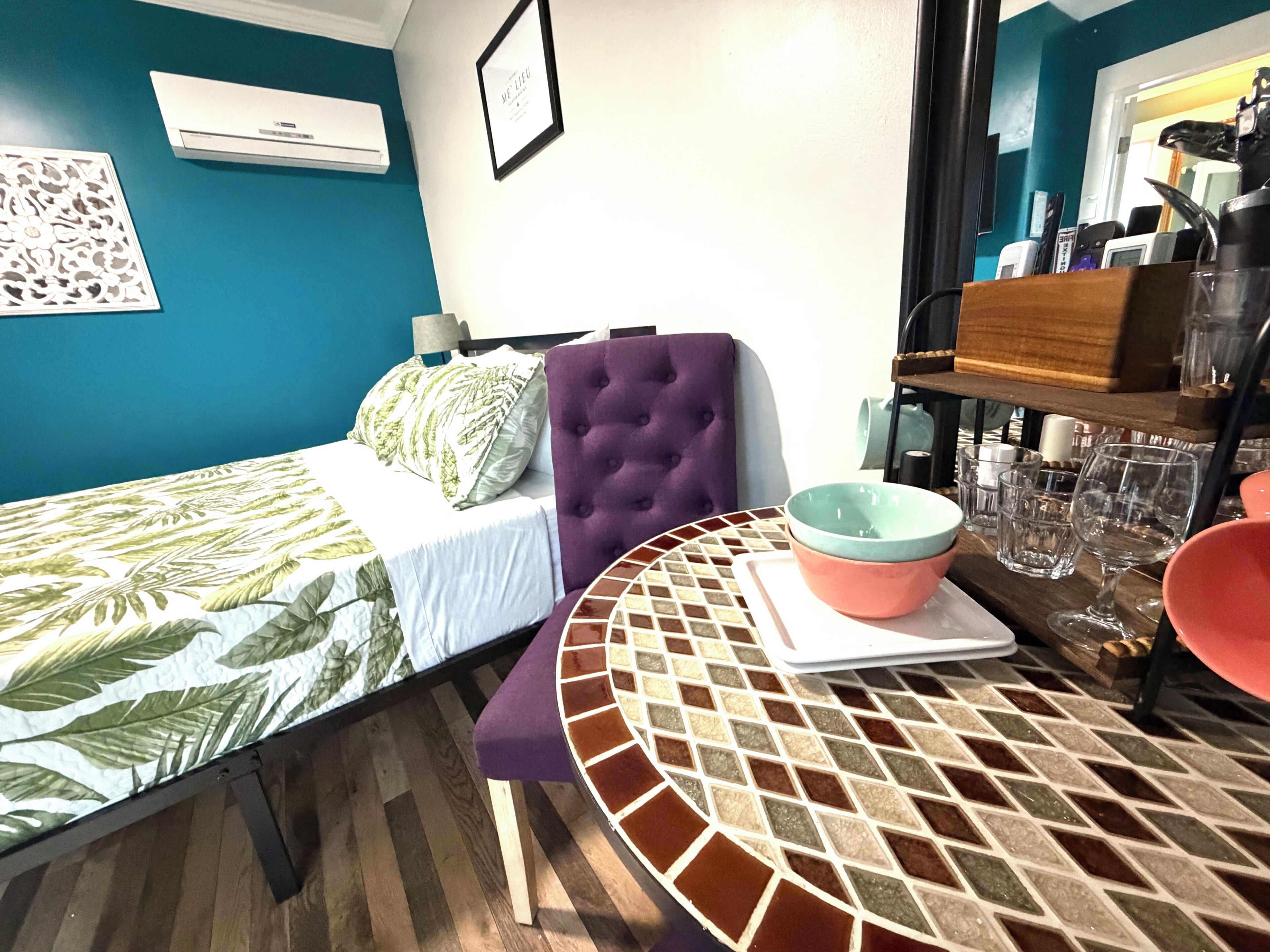 Ein Zimmer mit einem Bett, einem Tisch mit einer Schüssel und einer Wand-Klimaanlage.