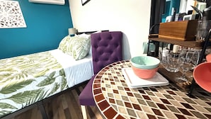 A room with a bed, a table with a bowl, and a wall-mounted air conditioner.