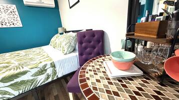 Ein Zimmer mit einem Bett, einem Tisch mit einer Schüssel und einer Wand-Klimaanlage.