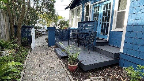 A blue house with a paved patio, a small outdoor seating area, and a garden with potted plants. - Walking distance to St George, packed with attractions and activities! (St. Augustine)