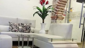 Un salon moderne avec un canapé blanc, une table basse en verre et une plante en pot.