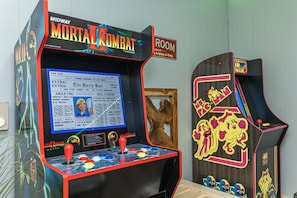 A Midway Mortal Kombat arcade machine in a room with a wooden door and a framed picture on the wall. - Lake Chalet Private Beach Hot Tub Fire Pit Skiing Golf Walkable to the Lake. (Lake Harmony)