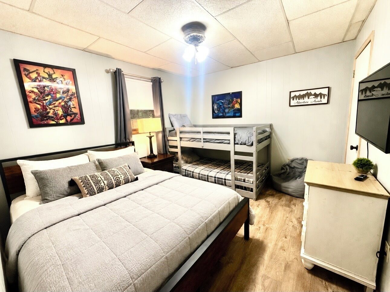 Ein Schlafzimmer mit einem Bett, Etagenbetten, einem Schreibtisch und einem Fernseher.