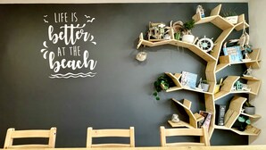 Un comedor con una pared de pizarra que presenta una cita motivacional, una estantería de madera con varios objetos decorativos y dos sillas de madera.