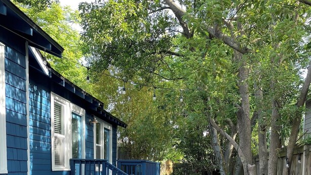 A blue house with a paved pathway leading to a blue porch.