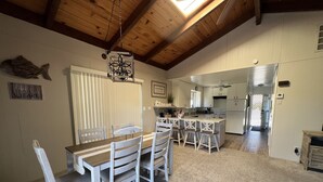 A spacious kitchen with a central island, wooden ceiling beams, and a dining area with a large table and chairs.