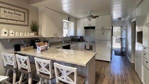 A modern kitchen with white cabinetry, a granite countertop, and a central island with bar stools.