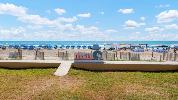 Vista de la playa con un cartel que anuncia 'The Tiki Vacation Condominiums'.