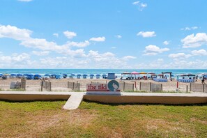 A beach with umbrellas, lounge chairs, and a sign for 'The tiki Vacation Condominiums'.