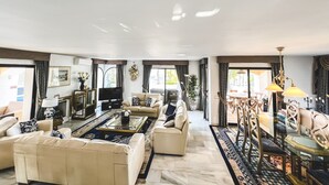 En rummelig stue med en stor sofa, et sofabord og et spiseområde med stole og et bord.