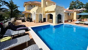 Et tosidet hus med swimmingpool, udendørs siddepladser og udsigt over det omkringliggende landskab.