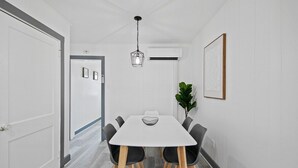 A dining area with a white table, black chairs, and a hanging light fixture.