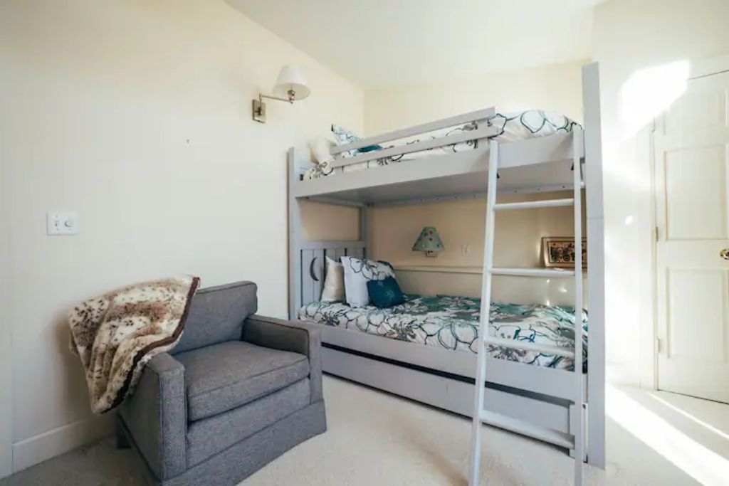 A bunk bed room with a grey sofa and a blanket.