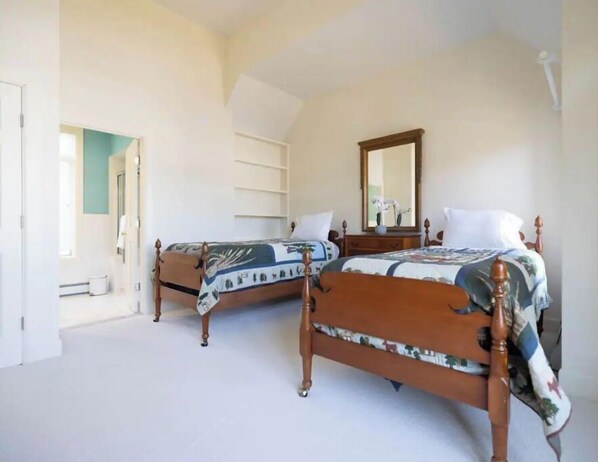A bedroom with two wooden beds, a large mirror, and a white door.