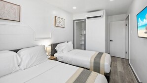A hotel room with two beds, a wardrobe, and a door leading to a bathroom. - Shorehaven 7- Updated and Stylish 2 bedroom 14 St! (Ocean City)