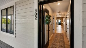 A hallway with a wooden floor, a number '302' on the wall, and a door leading to a room with a view. - 302 with a View! Luxury 2 bed 2 bath condo with amazing views of Sister Bay (Sister Bay)