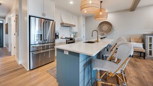 A modern kitchen with stainless steel appliances, a central island with bar seating, and a hanging light fixture. - 302 with a View! Luxury 2 bed 2 bath condo with amazing views of Sister Bay (Sister Bay)