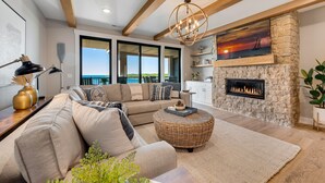A modern living room with a stone fireplace, large windows, and a view of the sea. - 302 with a View! Luxury 2 bed 2 bath condo with amazing views of Sister Bay (Sister Bay)