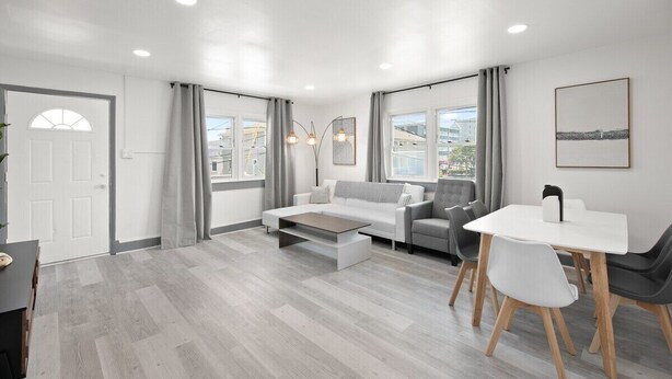A modern living room with a sofa, coffee table, and dining area.