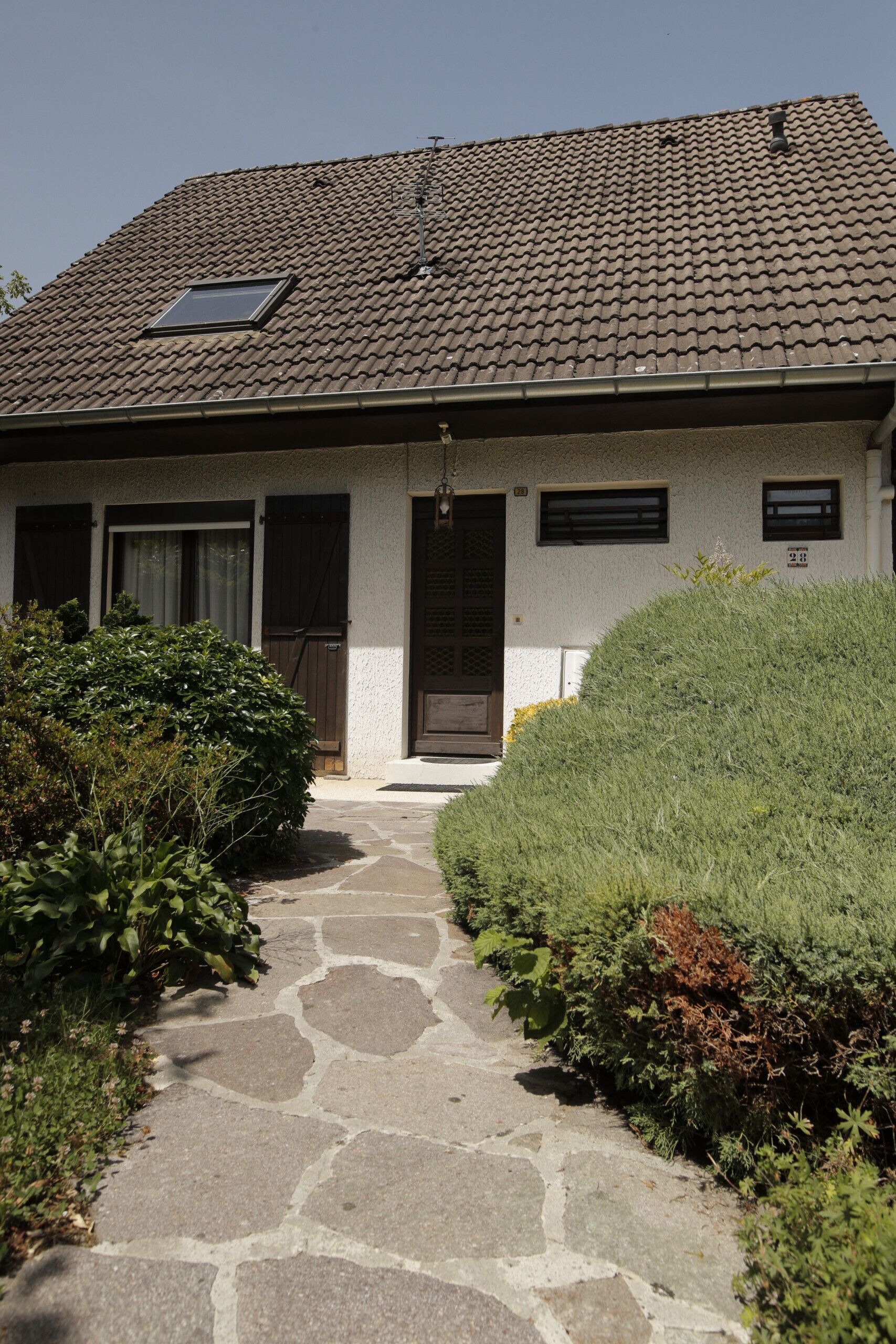 A house with a tiled roof, a stone pathway, and a well-maintained garden.