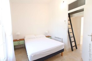 Ein Schlafzimmer mit einem Bett, einem Nachttisch, einer Lampe und einer Leiter.