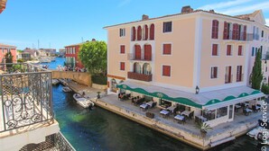 Un edificio frente al agua con terraza al aire libre, un canal y barcos.