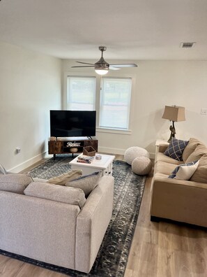 Relax in this stylish living room with a flat-screen TV, comfortable sofas, and a floor lamp.