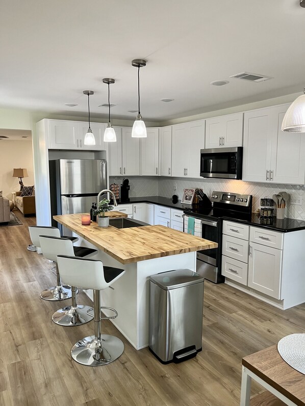 Enjoy cooking in this well-equipped kitchen with a central island, refrigerator, and microwave.