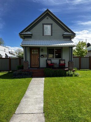 A single-story house with a front porch, a small brick chimney, and a pathway leading to the door. - Quaint 2 bedroom, 1 Bath home close to downtown Whitefish, Montana (Whitefish)